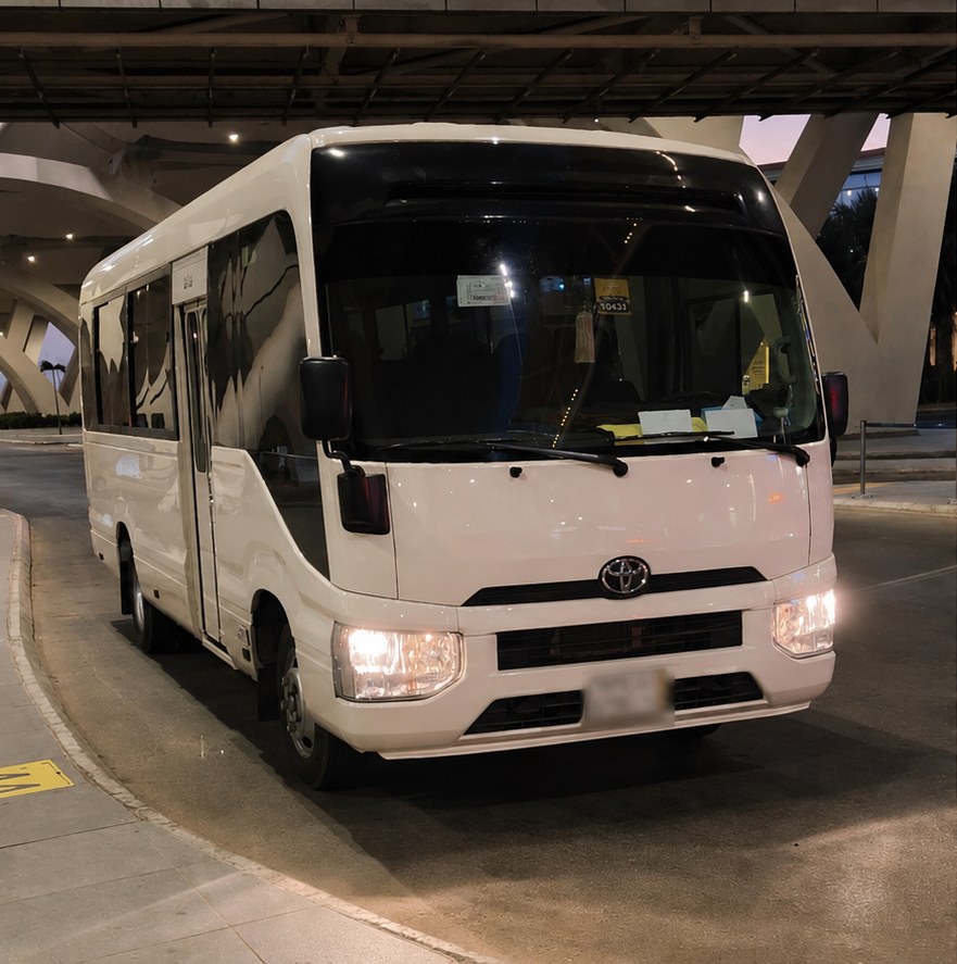 White Toyota Coaster minibus waiting at the airport terminal for a group transfer